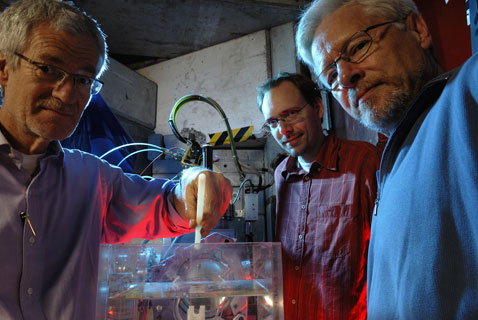 Слева направо: участники проекта ACE Михаэль Хольцшайтер (Michael Holzscheiter), Нильс Басслер (Niels Bassler) и Хельге Кнудсен (Helge Knudsen) перед экспериментальной установкой проекта (фото Maximilien Brice, Carolyn Lee).